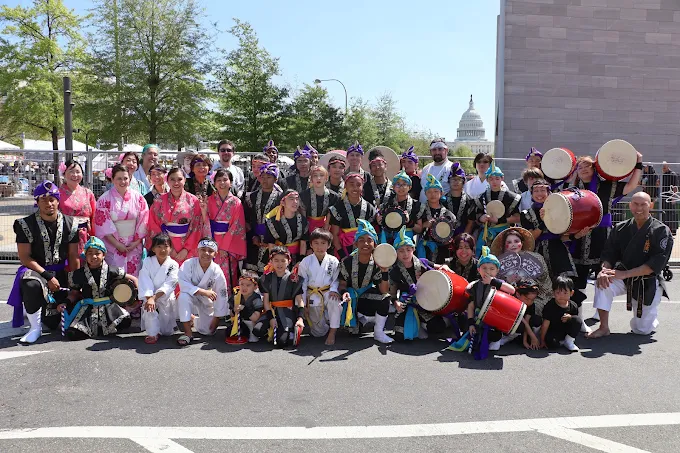 The Okinawa Karate & Cultural Center performance team — Eisa drummers, dancers, and karate students — at the National Cherry Blossom Festival with the U.S. Capitol behind them